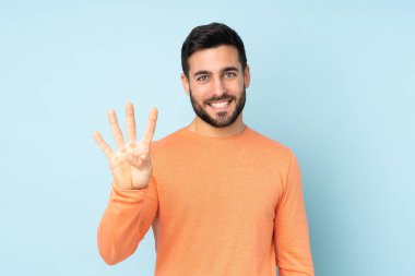 Kafkasyalı yakışıklı adam mutlu ve mavi arka planda parmakları olan dört kişi sayıyor.