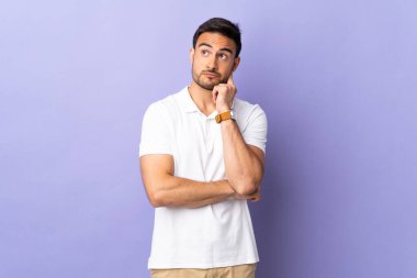 Mor arka planda soyutlanmış genç yakışıklı bir adam. Şüpheleri ve düşünceleri var.