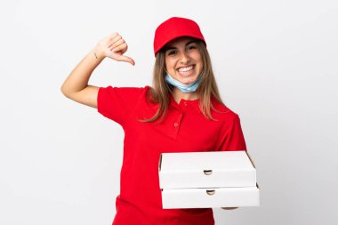 Pizza teslimatı yapan kadın elinde pizza tutuyordu. Koronavirüsten koruyordu. İzole edilmiş beyaz bir duvarın üzerinde gururlu ve kendini beğenmiş bir maskeyle.