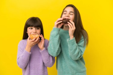 İzole edilmiş arka planda donut tutan kız kardeşler