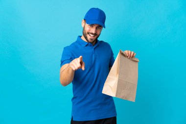 Mavi arka planda sakallı teslimatçı kendine güvenen bir ifadeyle seni işaret ediyor.