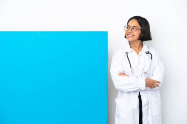 Beyaz arka planda izole edilmiş, mutlu ve gülümseyen büyük bir afişi olan genç ırk doktoru kadın.
