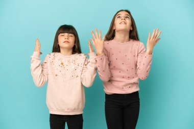 Küçük kız kardeşler mavi arka planda izole edilmiş kötü bir durum yüzünden hayal kırıklığına uğramış kızlar.