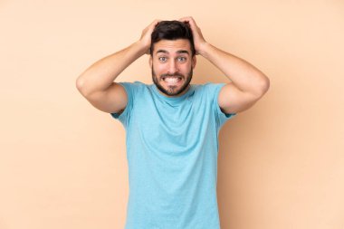 Beyaz tenli yakışıklı adam, bej arka planda izole edilmiş, gergin hareketler yapıyor.