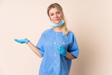 İzole edilmiş arka plan üzerinde araçları tutan dişçi kadın, el bilgisayarı üzerinde görsel alan tutuyor.