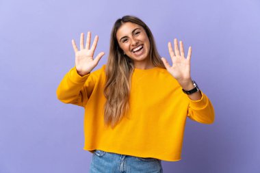 İzole edilmiş mor arka plan üzerinde genç İspanyol kadın parmaklarıyla ona kadar sayıyor.