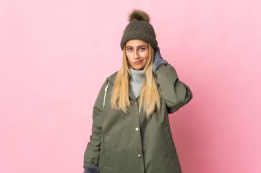 Pembe arka planda izole edilmiş, kış şapkalı genç kadın kuşkuları var.