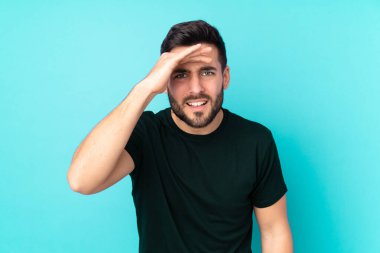 Beyaz tenli yakışıklı adam mavi arka planda izole edilmiş. Bir şeye bakmak için uzaklara bakıyor.