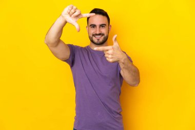 Sarı arka planda izole edilmiş beyaz yakışıklı bir adam. Odaklanan bir yüz. Çerçeve sembolü