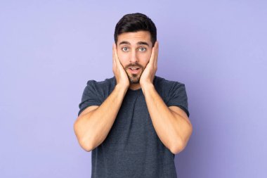 Kafkasyalı yakışıklı adam hayal kırıklığına uğramış ve mor arka plan yüzünden kulaklarını kapatmış.