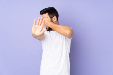 Kafkasyalı yakışıklı adam soyutlanmış arka planda jesti durduruyor ve yüzünü kapatıyor.