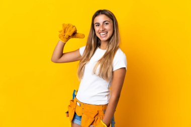 Genç İspanyol elektrikçi kadın izole edilmiş sarı duvarın üzerinde gururlu ve kendini beğenmiş.