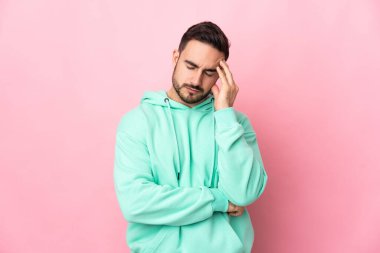 Pembe arka planda yalnız ve başı ağrıyan beyaz, yakışıklı genç bir adam.