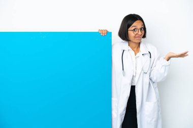 Beyaz arka planda izole edilmiş büyük bir afişi olan genç melez doktor kadın omuzlarını kaldırırken şüphe uyandırıyor.