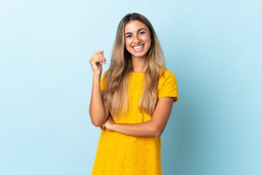 Soyutlanmış mavi arka planda genç İspanyol kadın gülüyor.
