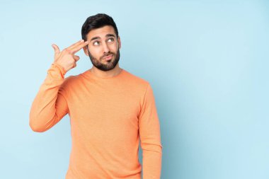İzole edilmiş mavi arka planda intihar jesti yapan beyaz, yakışıklı bir adam.