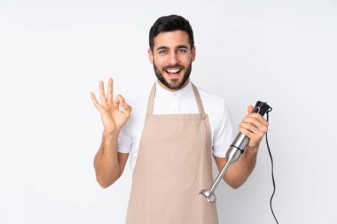 Beyaz arkaplanda izole edilmiş el blenderi kullanan bir adam parmaklarıyla tamam işareti gösteriyor