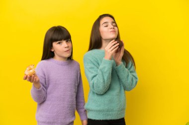 İzole edilmiş arka planda donut tutan kız kardeşler