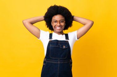 Genç Afrikalı Amerikalı kadın sarı arka planda yalnız gülüyor.