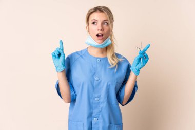 Dişçi kadın aletleri izole edilmiş arka plan üzerinde tutuyor işaret parmağı ile harika bir fikir.