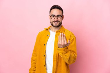 Pembe arka planda soyutlanmış beyaz, yakışıklı genç bir adam, bizimle gelmesi için davet ediyor. Gelmene sevindim.