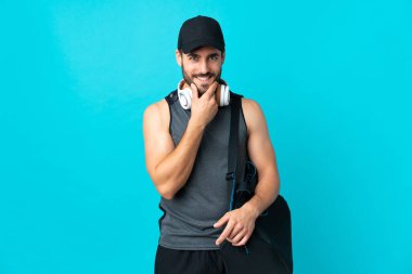 Spor çantalı genç adam mavi arka planda izole edilmiş.