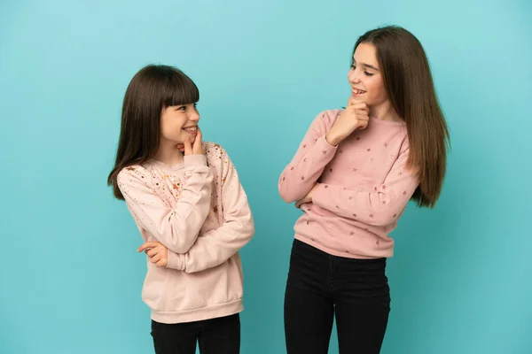 Hermanitas Niñas Aisladas Sobre Fondo Azul Mirando Uno Otro —  Fotos de Stock