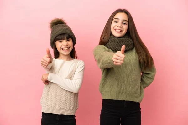 Hermanitas Vestidas Con Ropa Invierno Aisladas Sobre Fondo Rosa Dando —  Fotos de Stock