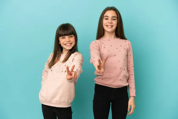 Hermanitas Niñas Aisladas Sobre Fondo Azul Sonriendo Mostrando Signo Victoria —  Fotos de Stock