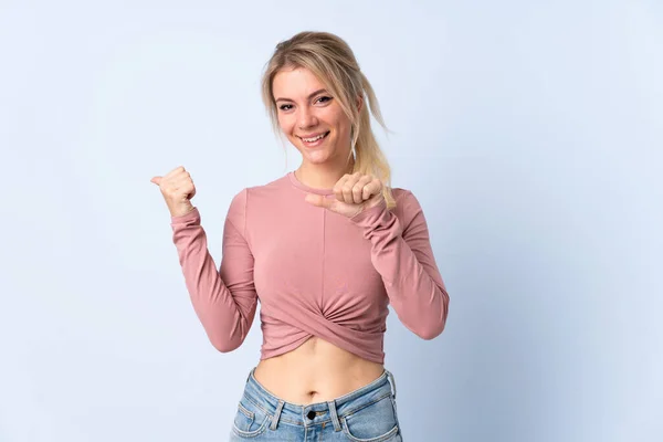 Blond Vrouw Geïsoleerde Blauwe Achtergrond Wijzend Naar Zijkant Een Product — Stockfoto