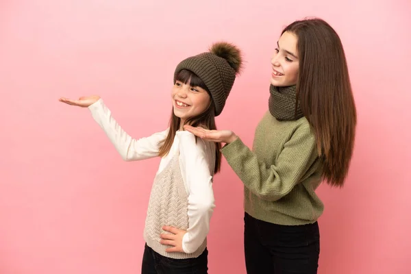 Hermanitas Vestidas Con Ropa Invierno Aisladas Sobre Fondo Rosa Apuntando — Foto de Stock