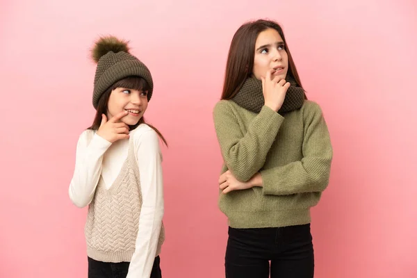 Irmãzinhas Vestindo Uma Roupa Inverno Isolada Fundo Rosa Com Dúvidas — Fotografia de Stock