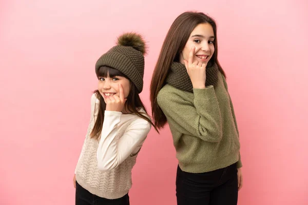 Hermanitas Vestidas Con Ropa Invierno Aisladas Sobre Fondo Rosa Mirando —  Fotos de Stock