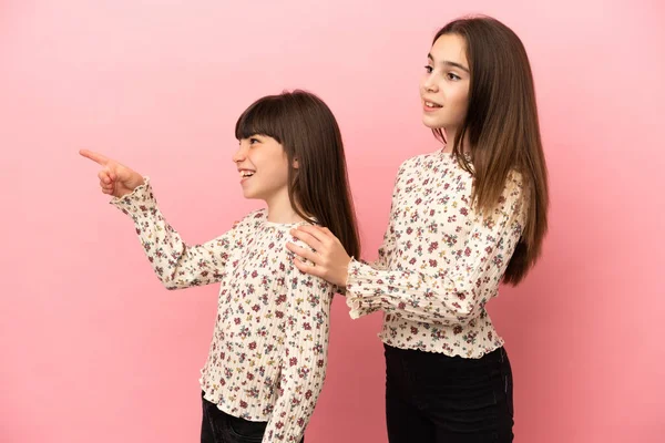 Μικρές Αδελφές Κορίτσια Απομονωμένες Ροζ Φόντο Που Δείχνουν Στο Πλάι — Φωτογραφία Αρχείου