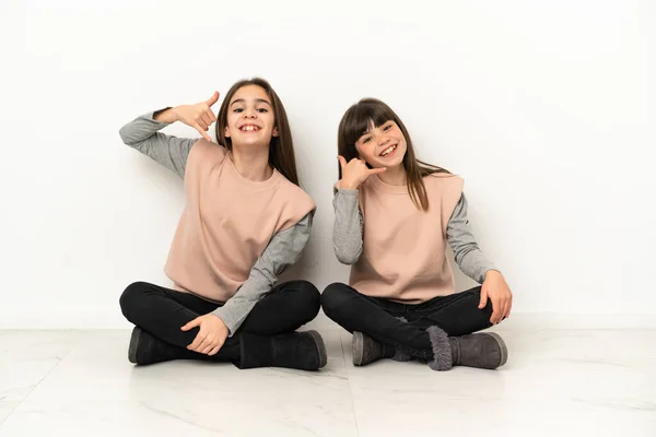 Hermanitas Sentadas Suelo Aisladas Sobre Fondo Blanco Haciendo Gesto Telefónico —  Fotos de Stock