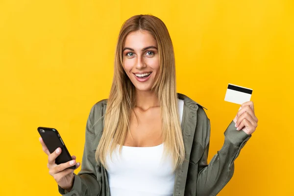 Mladá Blondýnka Izolované Žlutém Pozadí Nákup Mobilem Držící Kreditní Kartu — Stock fotografie