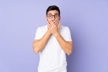 Kafkasyalı yakışıklı adam izole edilmiş arka planda ağzı elleriyle kapatıyor.