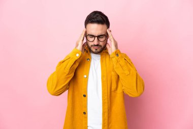 Pembe arka planda yalnız ve başı ağrıyan beyaz, yakışıklı genç bir adam.