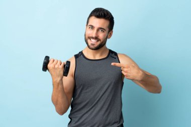 Sakallı genç sporcu ağırlık kaldırıyor ve onu doğrultuyor.