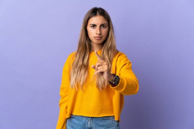 Tecrit edilmiş mor arka planda genç bir İspanyol kadın hayal kırıklığına uğramış ve ön tarafı işaret ediyor.