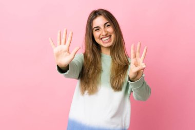 Soyutlanmış pembe arka planda genç bir kadın parmaklarıyla sekiz sayıyor.