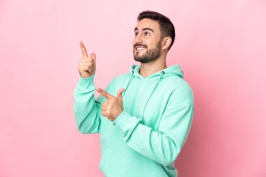 Pembe arka planda izole edilmiş genç beyaz adam işaret parmağıyla işaret etmek harika bir fikir.