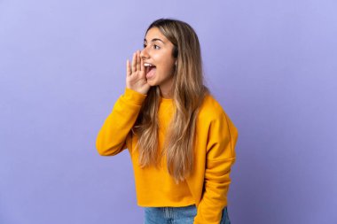 İzole edilmiş mor arka planda ağzı sonuna kadar açık bağıran genç İspanyol kadın.