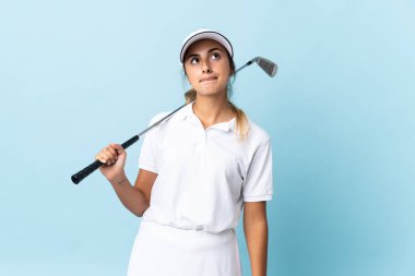 Genç İspanyol golfçü kadın izole edilmiş mavi duvardan yukarı bakıyor.