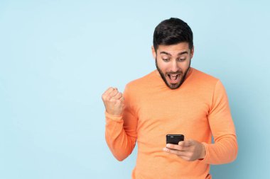 Kafkas yakışıklı adam şaşırdı ve izole edilmiş mavi arka plan üzerinden bir mesaj gönderiyor.