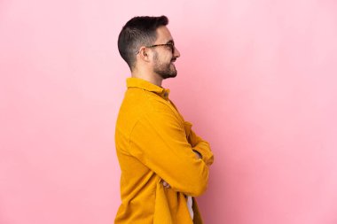 Beyaz tenli yakışıklı adam, pembe arka planda, yan pozisyonda izole edilmiş.