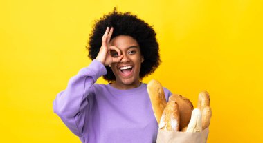 Genç Afrikalı Amerikalı bir kadın sarı arka planda izole edilmiş bir şey alıyor.