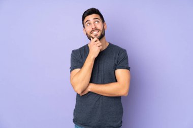 Kafkasyalı yakışıklı bir adam, izole edilmiş mor arka plana bakarken bir fikir düşünüyor.