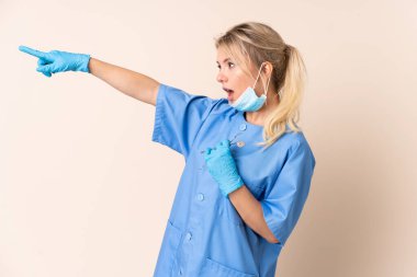 İzole edilmiş arka plan üzerinde aletleri tutan dişçi kadın parmak kenarı işaret ediyor