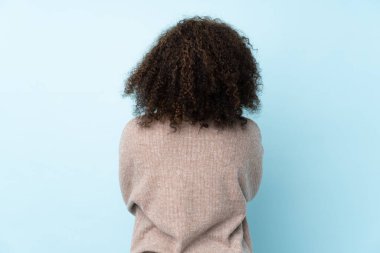 Genç Afrikalı Amerikalı kadın arka planda mavi arka planda izole edilmiş.